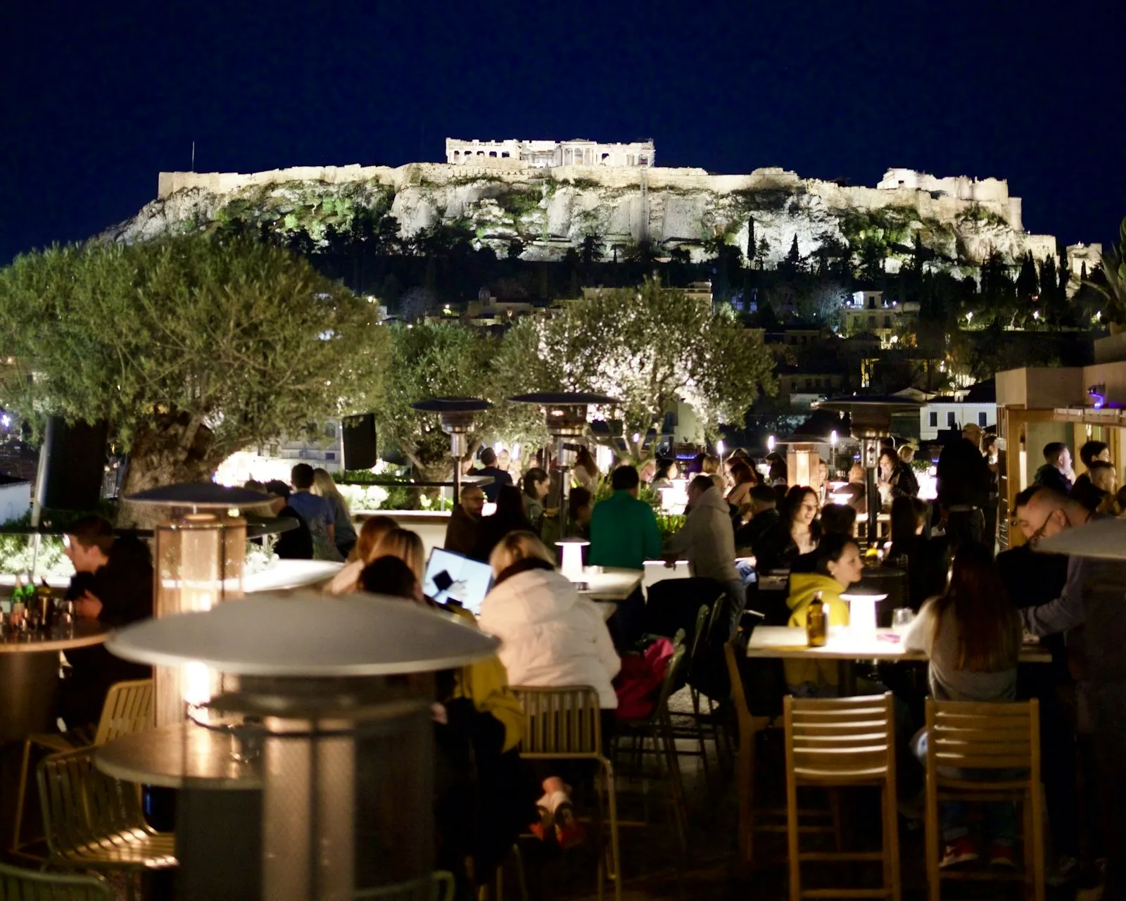 Rooftop bar at night with the lit Acropolis behind